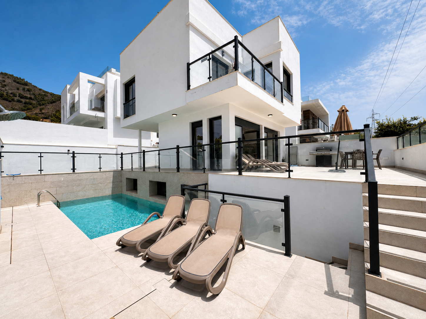 Outdoor pool area with loungers and white facade