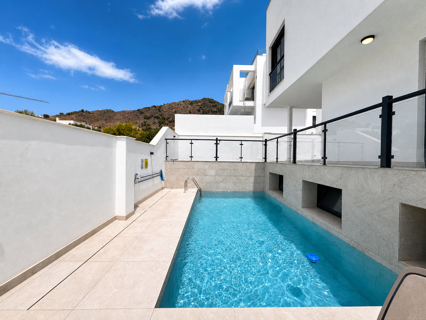 Narrow pool with loungers and perimeter wall