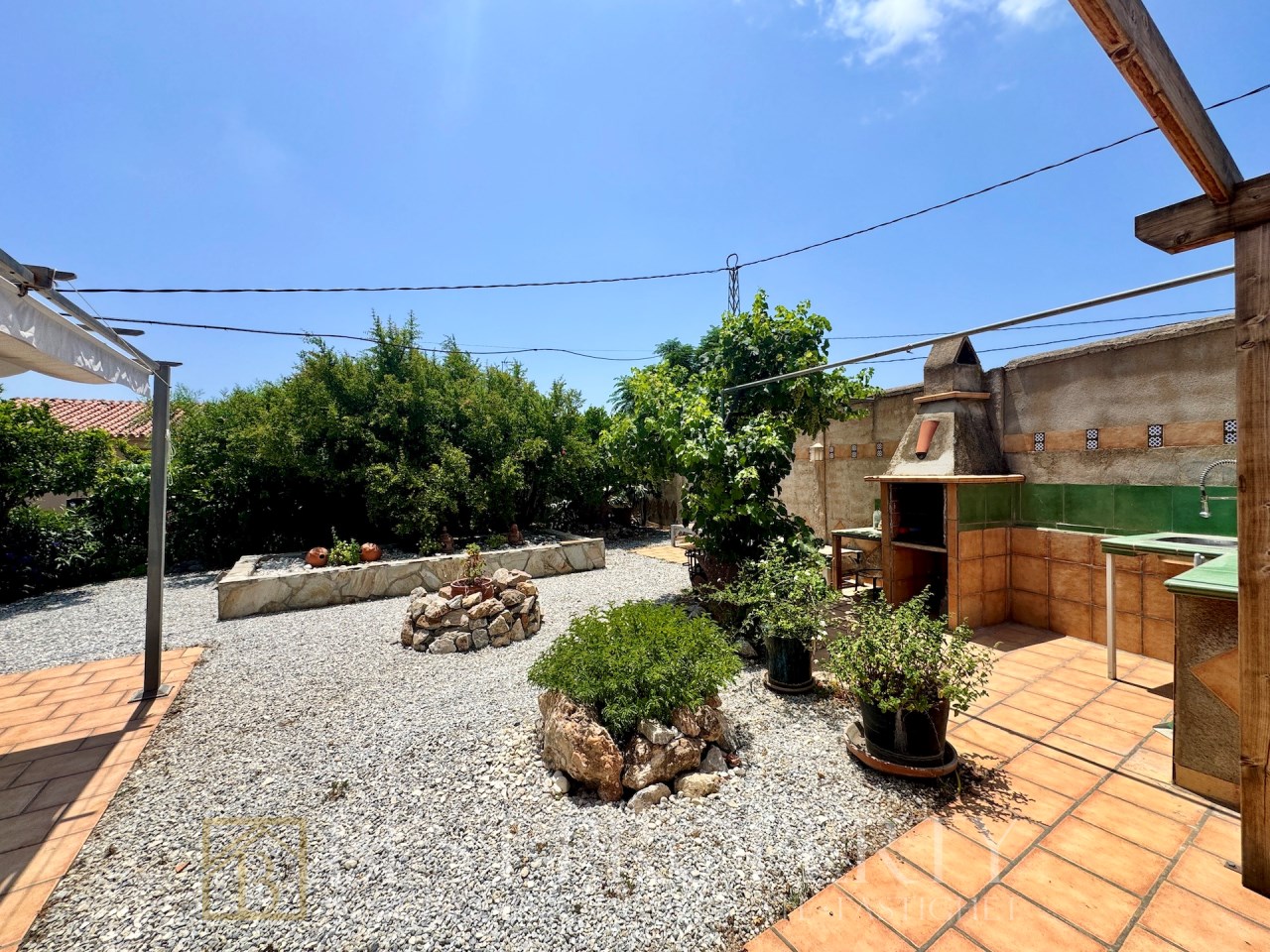 Garden with gravel, trees and barbecue area