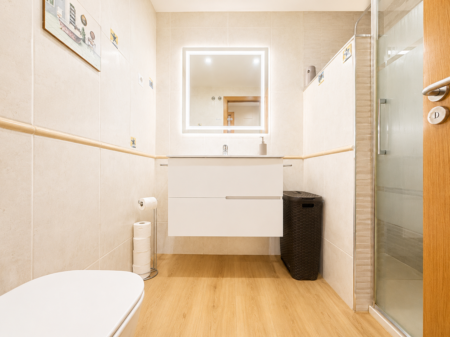 Bathroom with shower, lit sink and glass screen