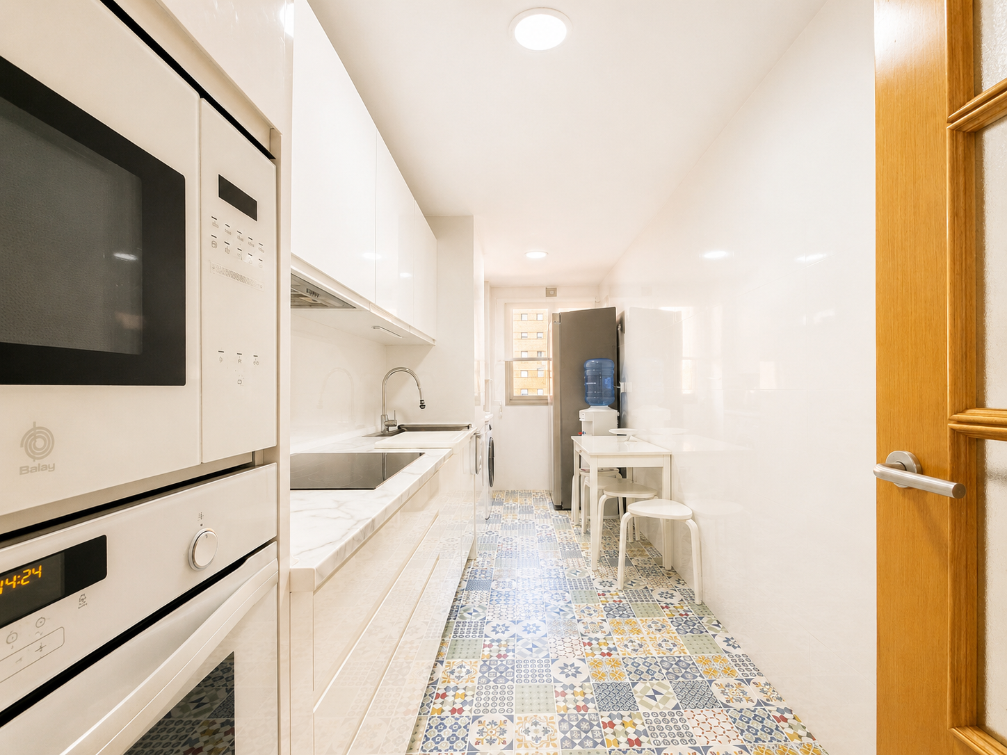 Long kitchen with white cabinets and built-in appliances