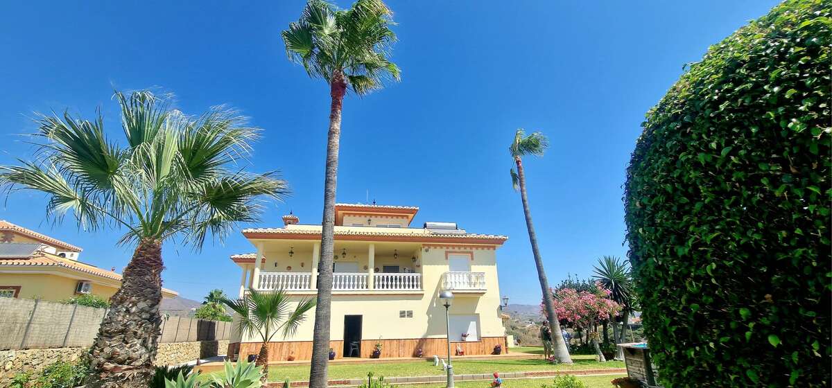 Front facade of villa with garden and palms