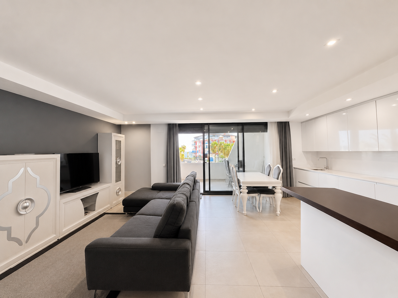 Spacious living room with black sofa and integrated dining area