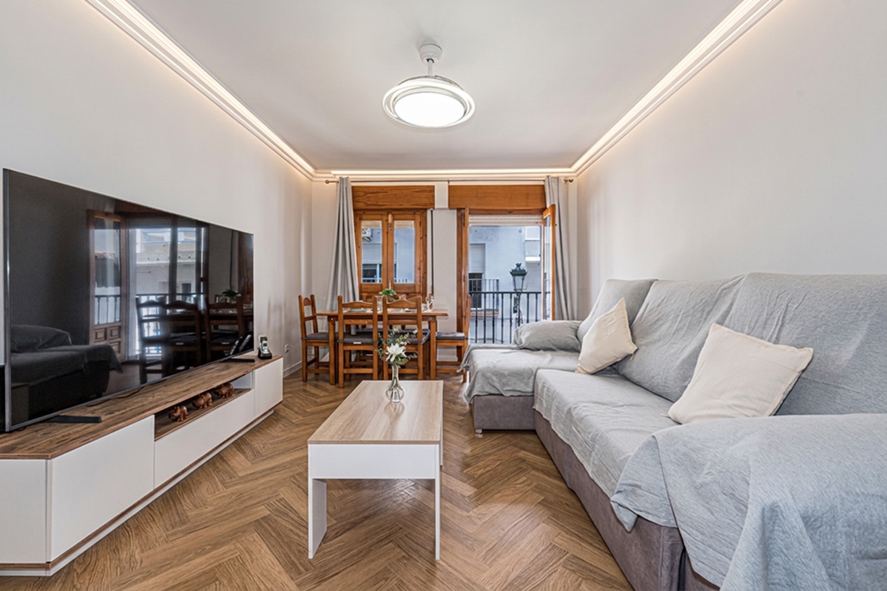 Bright living-dining room with sofa, TV and balcony