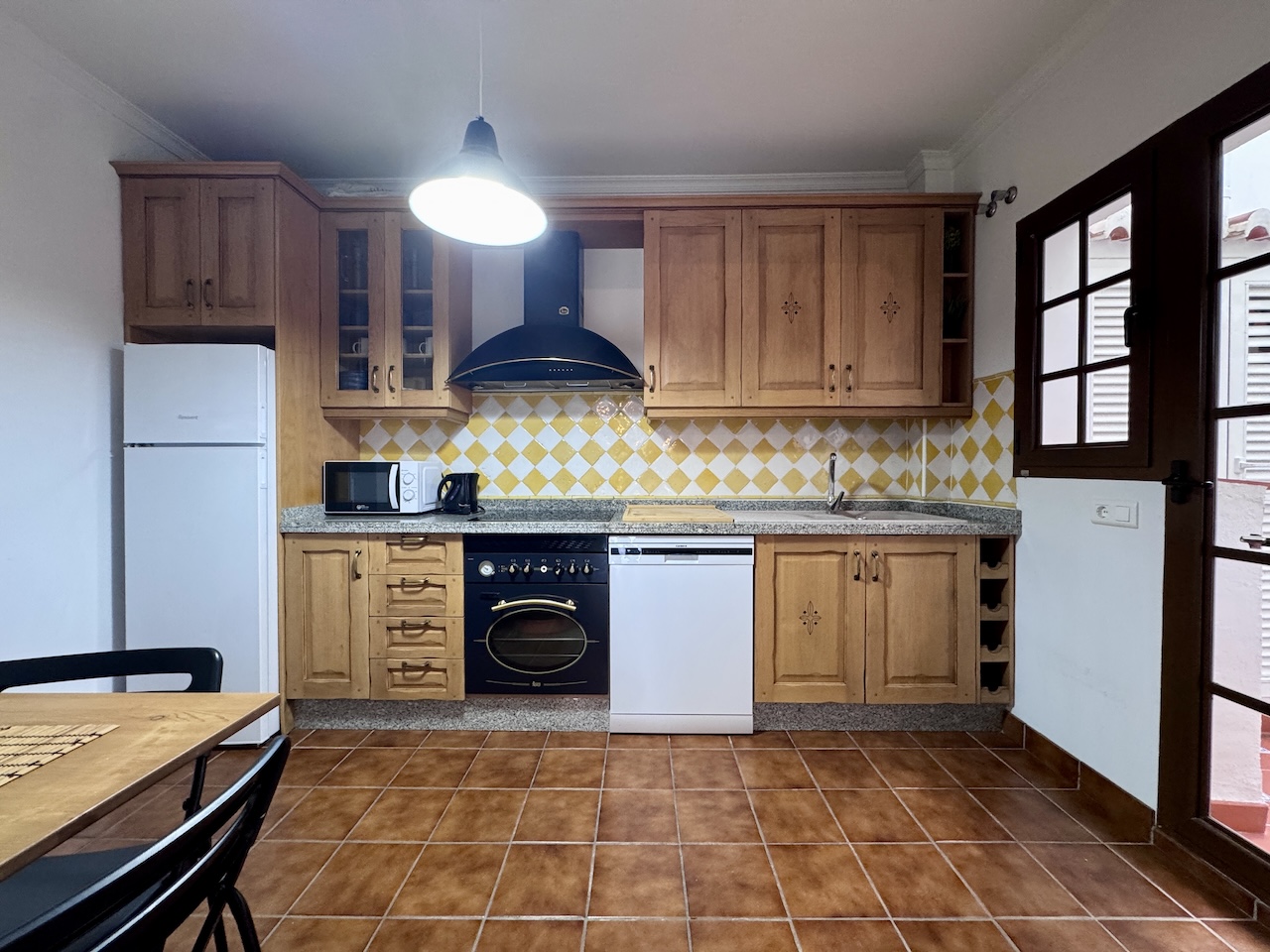 Equipped kitchen with wooden cabinets and dining area