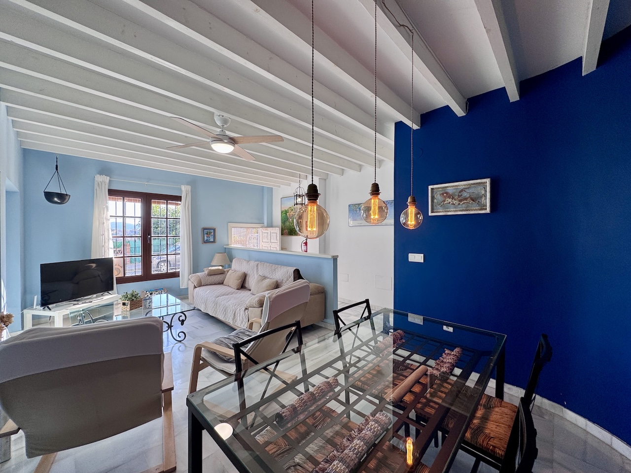 Bright living room with sofa, TV and dining area