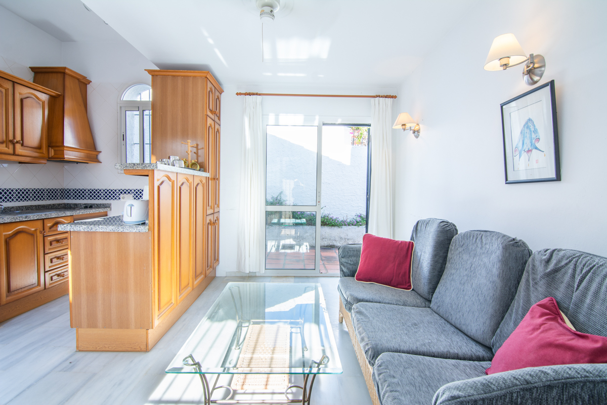 Living room with sofa, open kitchen and patio access