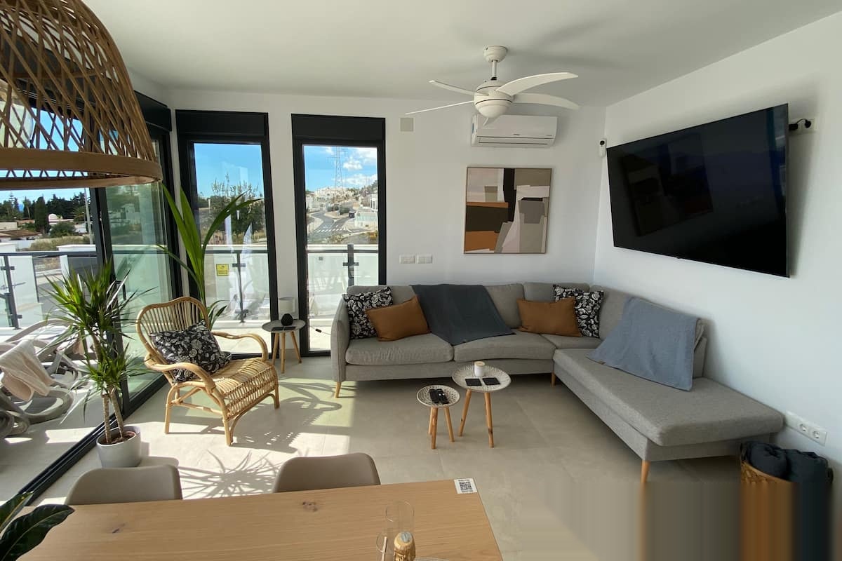 Bright living room with sofa, TV and terrace access