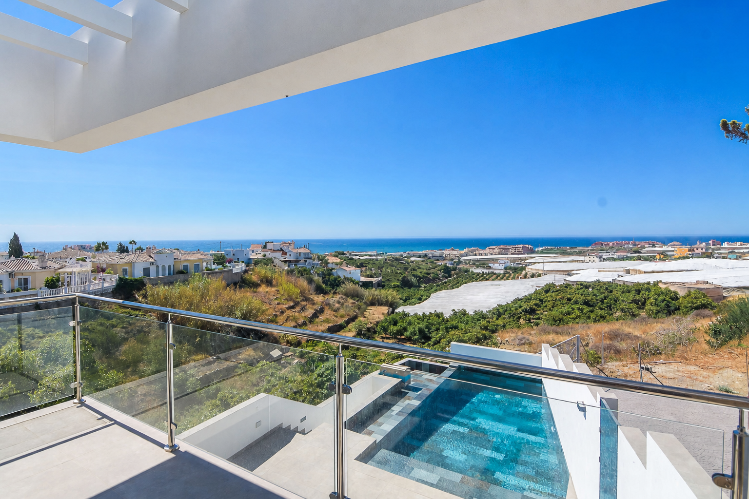 Terrace with glass railing, pool and sea views