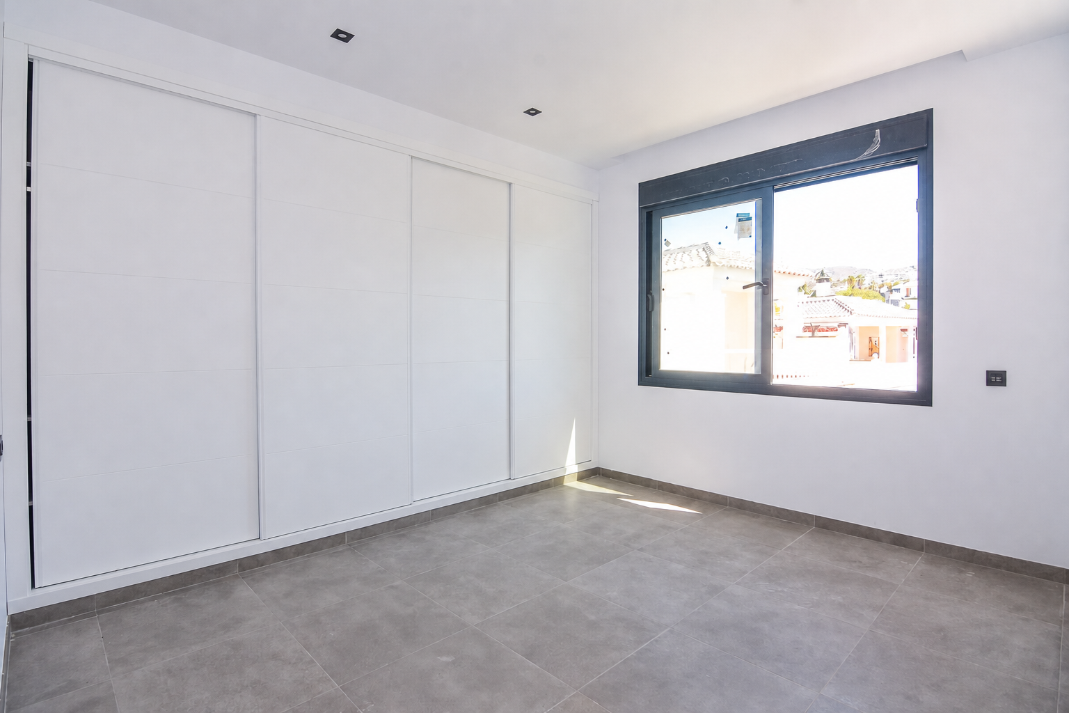 Empty bedroom with built-in wardrobe and window